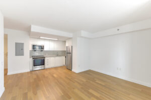 Interior Unit Living Room, wood floors, stainless steel appliances, white cabinets, open floor plan, white walls.