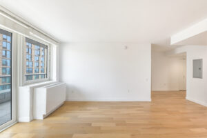 Interior Unit Living Room, White walls, wood floors, door to outdoor balcony.