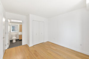 Interior Unit Bedroom, attached bathroom, wood floors, white walls, accordion closet doors.